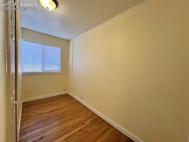 a view of an empty room with wooden floor and a window