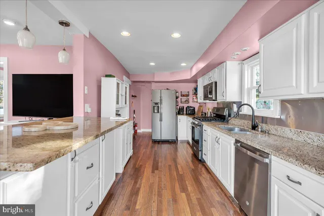 a large kitchen with stainless steel appliances kitchen island granite countertop a large counter top and a stove