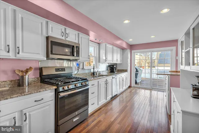 a kitchen with stainless steel appliances a stove a sink cabinets and a wooden floor