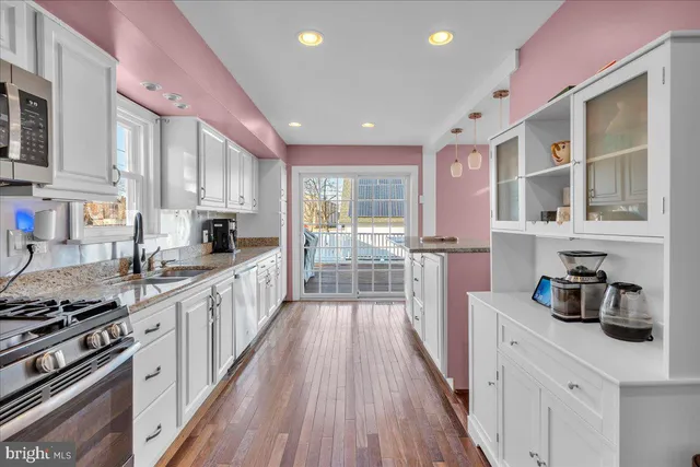 a kitchen with stainless steel appliances a sink and wooden floor