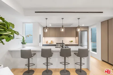 a kitchen with stainless steel appliances a table a refrigerator and cabinets