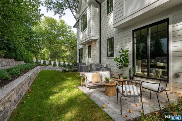 a view of a patio with table and chairs potted plants and floor to ceiling window