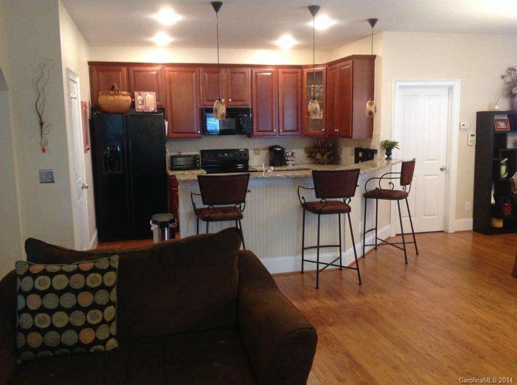 1195 Springmaid Avenue Fort Mill, SC 29708 - Photo 6 of 22 a kitchen with stainless steel appliances kitchen island granite countertop a refrigerator a stove a sink and a microwave with wooden floor