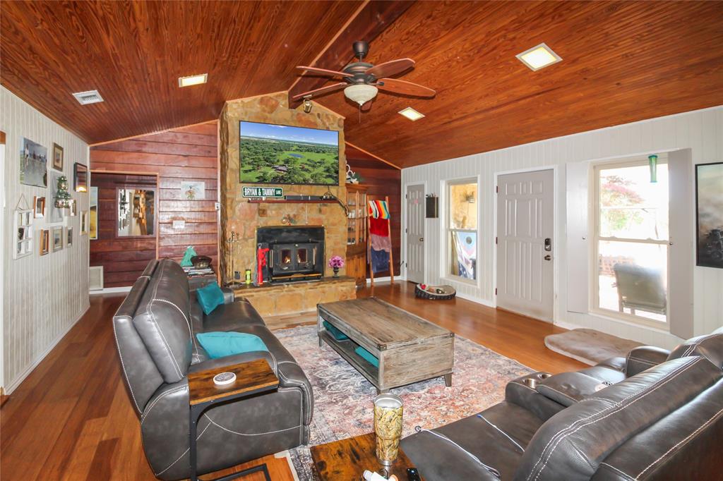 1001 Sandy Ridge Road Scurry, TX 75158 - Photo 13 of 35 Living area featuring a stone fireplace with hearth, wood-finish flooring, and a vaulted wood-paneled ceiling