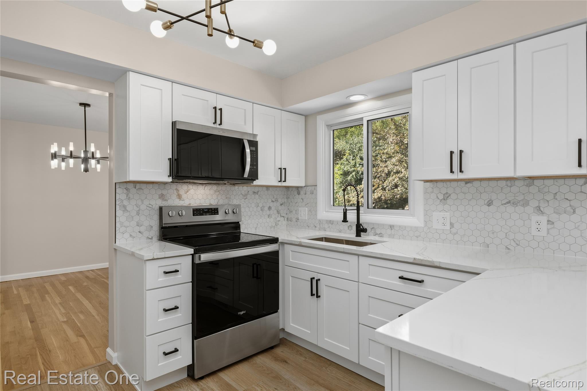 25695 Branchaster Road Farmington, MI 48336 - Photo 17 of 58 White shaker cabinetry, stone countertops, stainless steel appliances, hexagonal tile backsplash, and light wood-finish flooring
