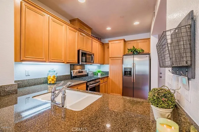 a kitchen with stainless steel appliances granite countertop a refrigerator a stove and a wooden cabinets