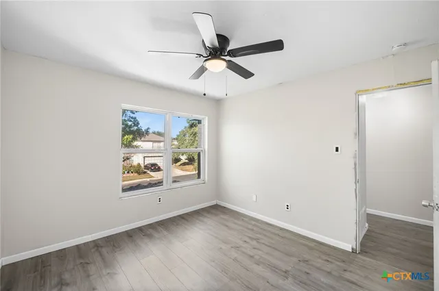 an empty room with window and ceiling fan