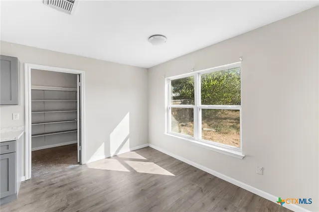 an empty room with wooden floor and windows