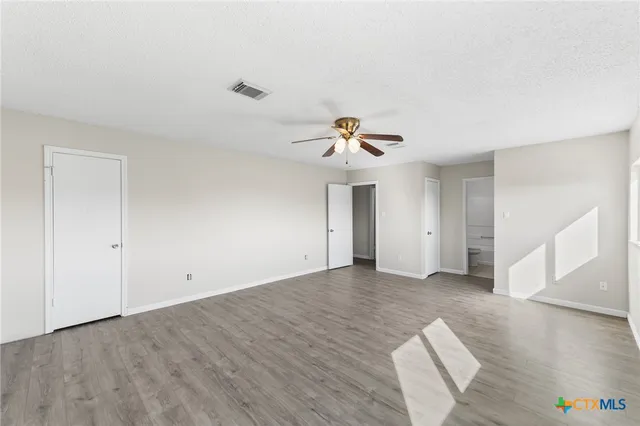 a view of empty room with wooden floor and ceiling fan