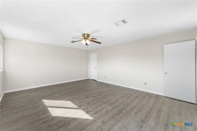 an empty room with wooden floor and ceiling fan