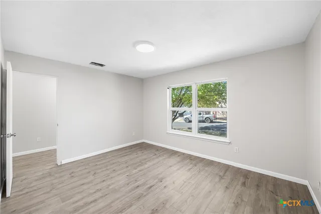 an empty room with wooden floor and windows