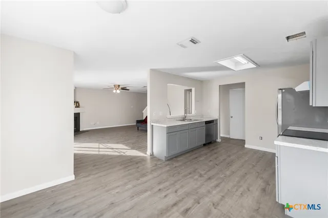 a view of a kitchen with a sink and dishwasher in white cabinet