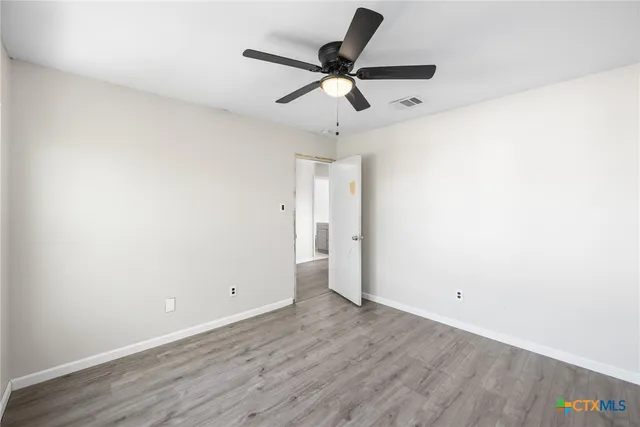 a view of a room with wooden floor and a ceiling fan