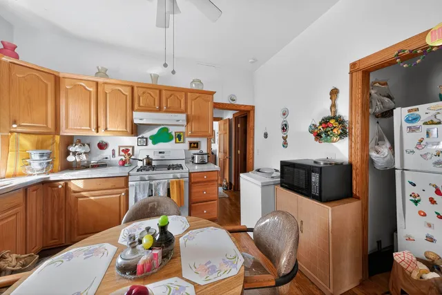 a kitchen with stainless steel appliances a stove a refrigerator a sink a dining table and chairs with wooden floor