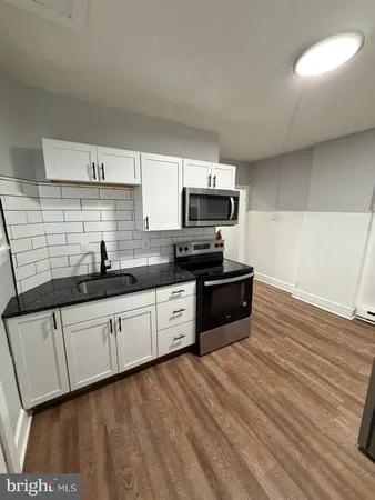 a kitchen with granite countertop a stove a sink and a microwave
