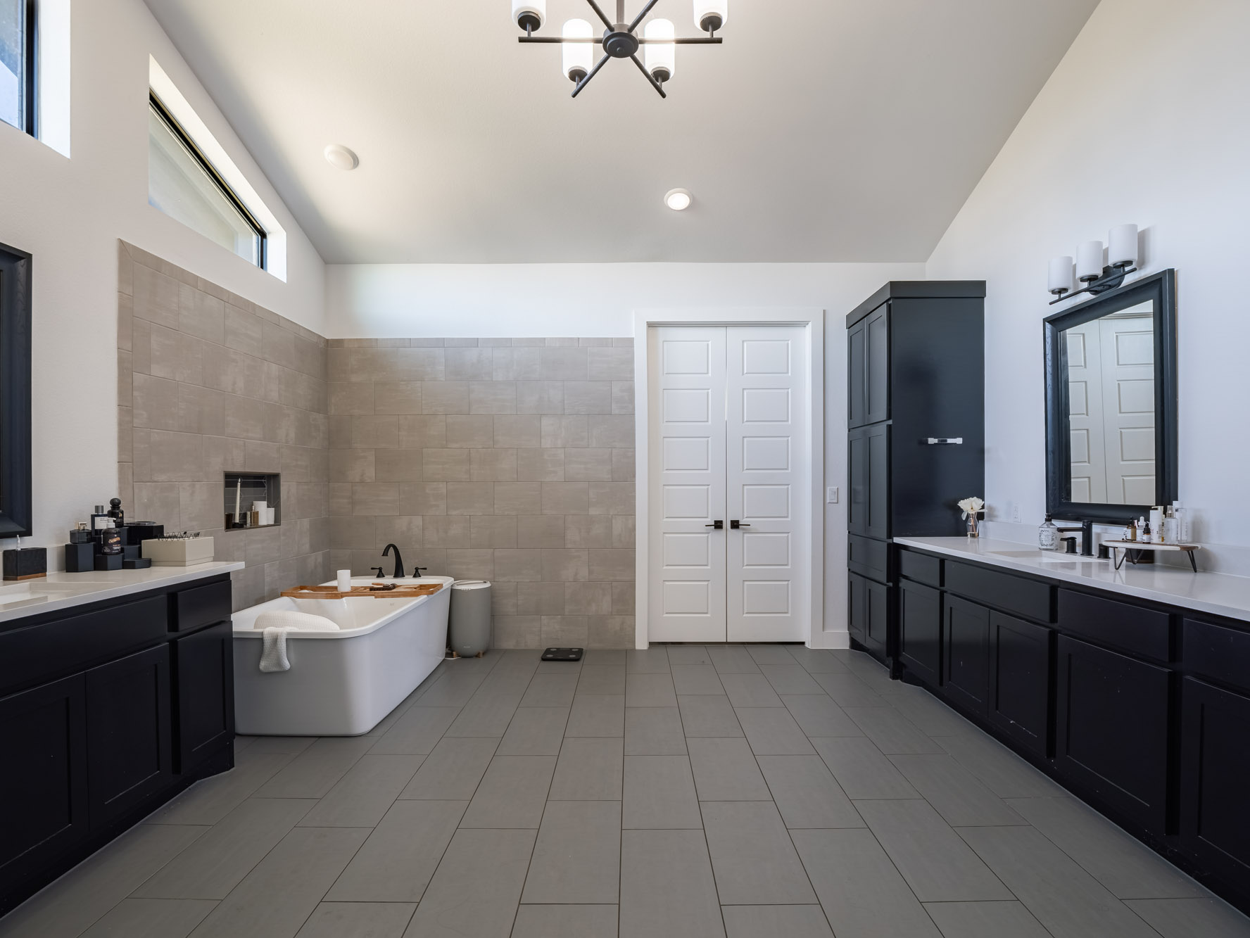 14900 Copper Ridge Lane Austin, TX 78734 - Photo 20 of 39 Full bathroom with vaulted ceiling, two vanities, a soaking tub, tile walls, and light tile patterned floors