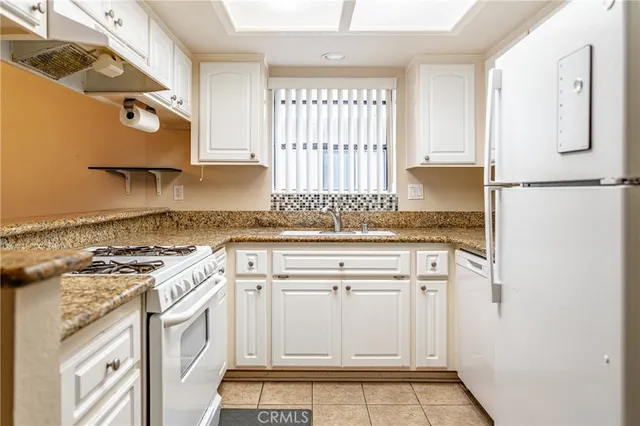 a kitchen with granite countertop white cabinets and white appliances
