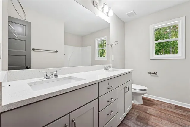 a bathroom with a double vanity sink toilet and a window