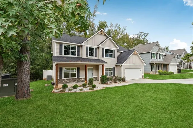 a front view of a house with a garden and trees
