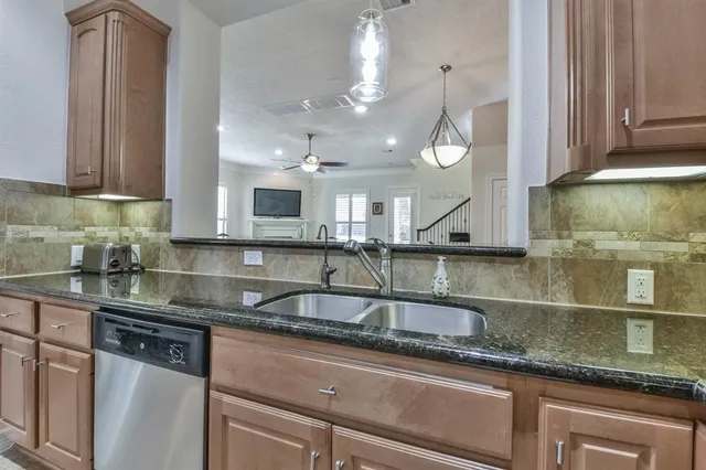 a kitchen with granite countertop a sink a counter space cabinets and stainless steel appliances