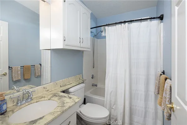 a bathroom with a granite countertop sink toilet and shower