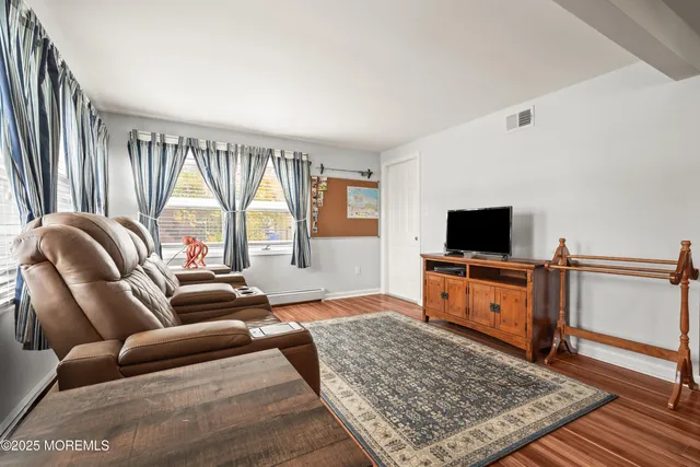 a kitchen with stainless steel appliances granite countertop a refrigerator a sink dishwasher a dining table and chairs with wooden floor