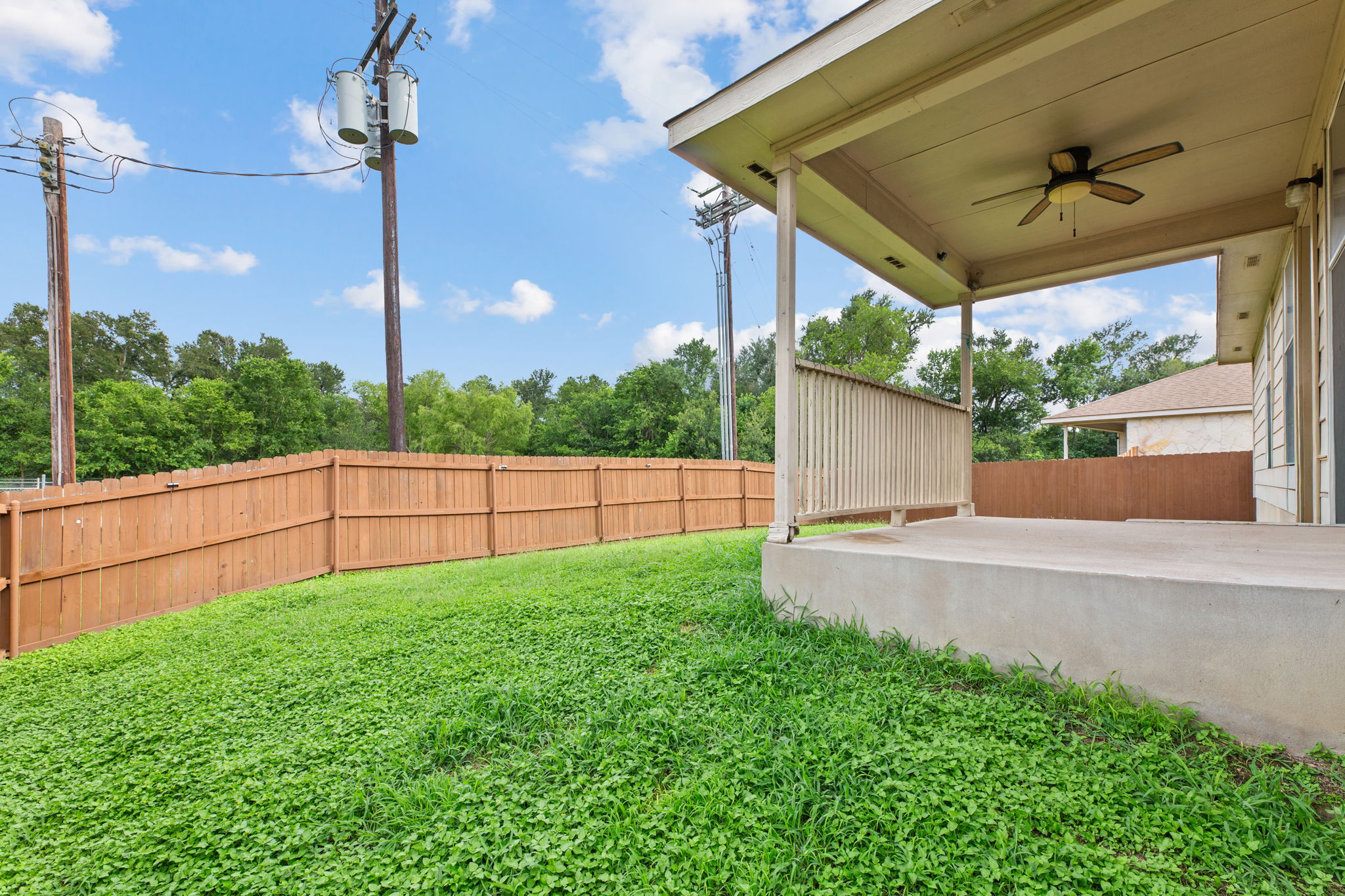 12601 Waynespur Lane Elgin, TX 78621 - Photo 35 of 38 A spacious backyard with a private fence, lush green grass, and a covered patio for outdoor relaxation.