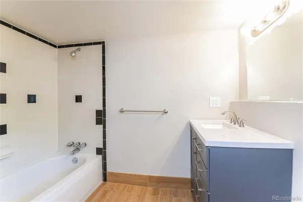 a bathroom with a bathtub shower sink vanity and mirror