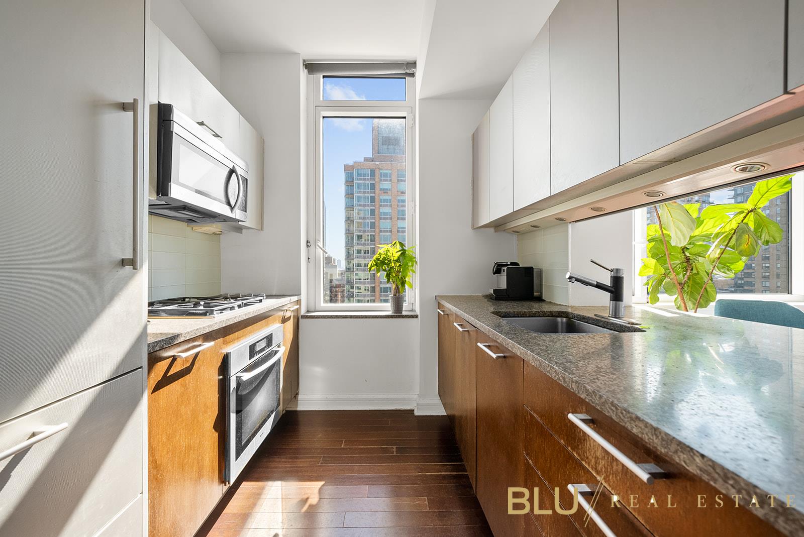 100 Riverside Boulevard, Unit 28E Manhattan, NY 10069 - Photo 2 of 6 a kitchen with stainless steel appliances granite countertop a sink a stove and a wooden floors