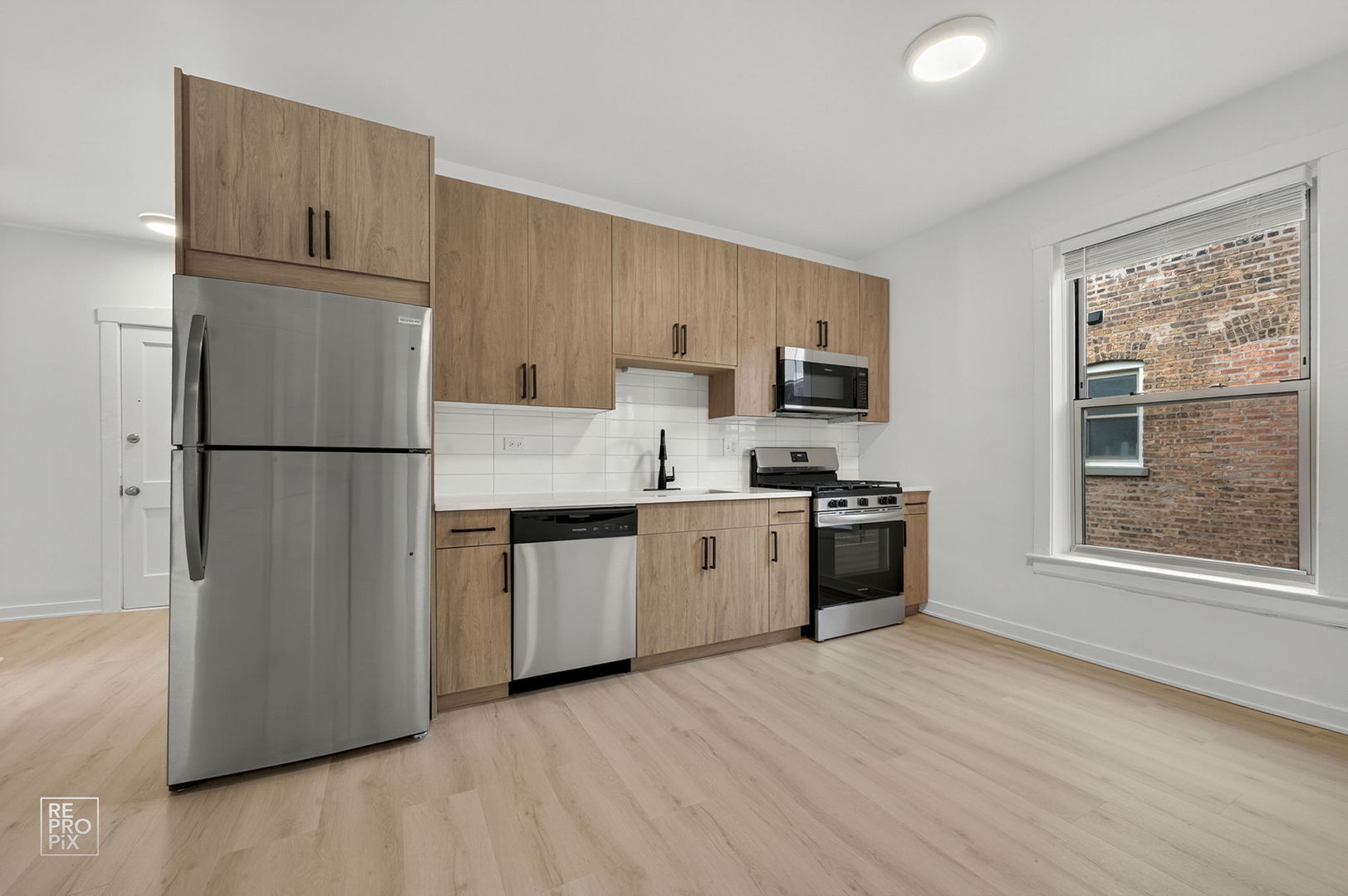 6975 North Bell Avenue, Unit 1 Chicago, IL 60645 - Photo 3 of 16 a kitchen with stainless steel appliances granite countertop a refrigerator oven a sink dishwasher and a refrigerator with wooden floor