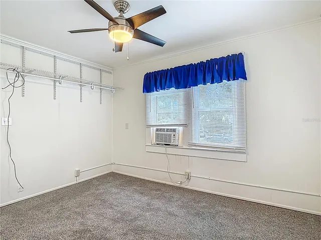 an empty room with windows and ceiling fan