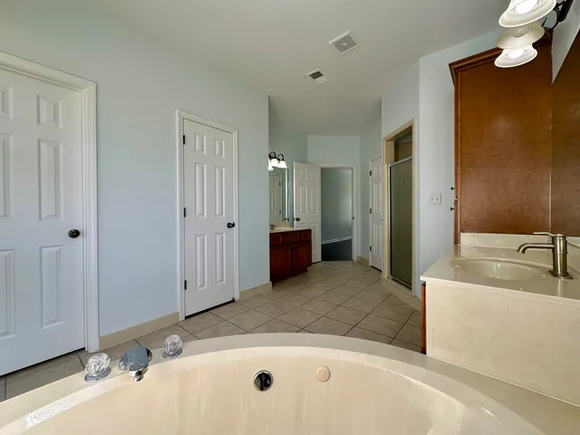 a spacious bathroom with a tub sink and mirror