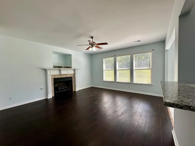 an empty room with wooden floor fireplace and windows