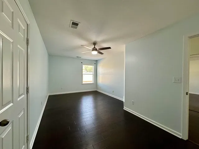 an empty room with wooden floor cabinet and windows
