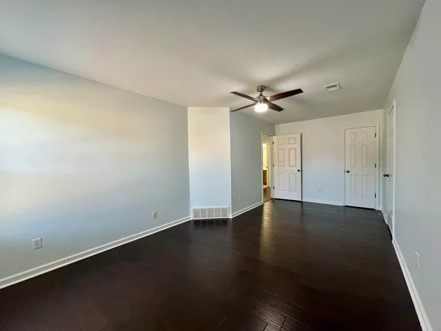 an empty room with wooden floor fan and windows