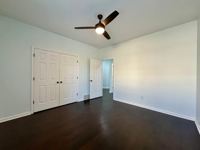 an empty room with wooden floor and ceiling fan