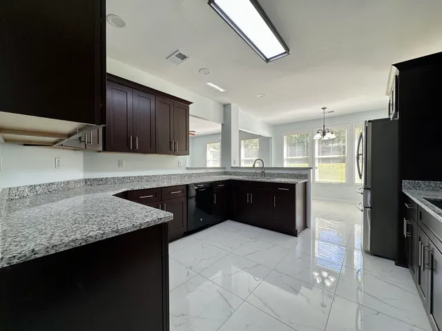 a kitchen with stainless steel appliances granite countertop a refrigerator a sink and a stove