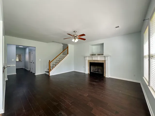 a view of an empty room with wooden floor fireplace and a window