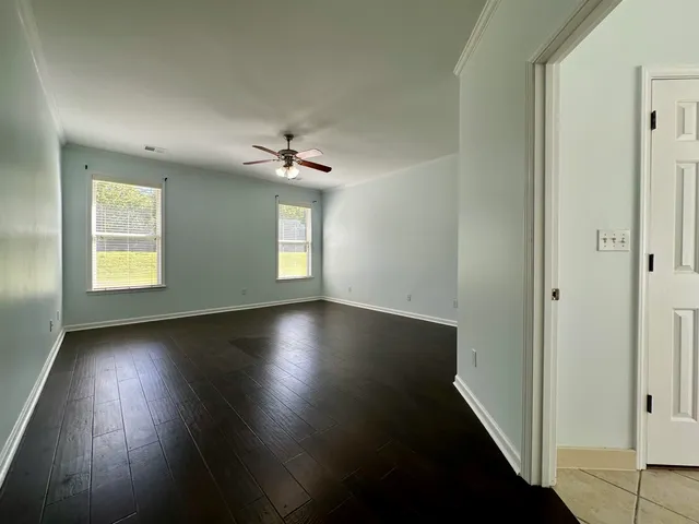 an empty room with wooden floor chandelier and windows