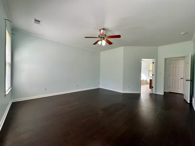 an empty room with wooden floor and chandelier fan