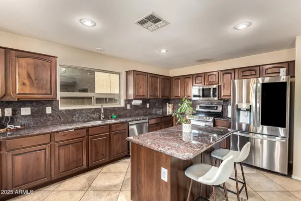 a kitchen with granite countertop stainless steel appliances a stove top oven a sink a dining table and chairs