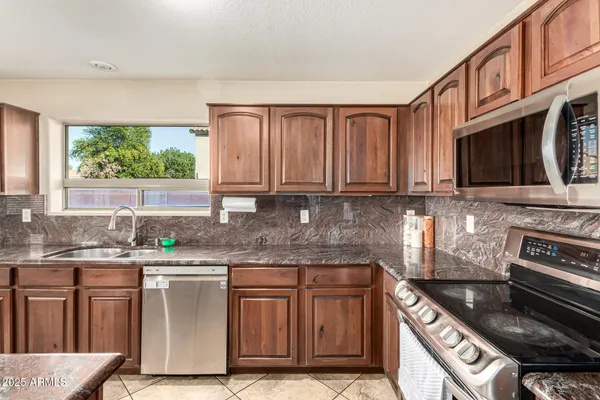 a kitchen with stainless steel appliances granite countertop a stove a sink and a microwave