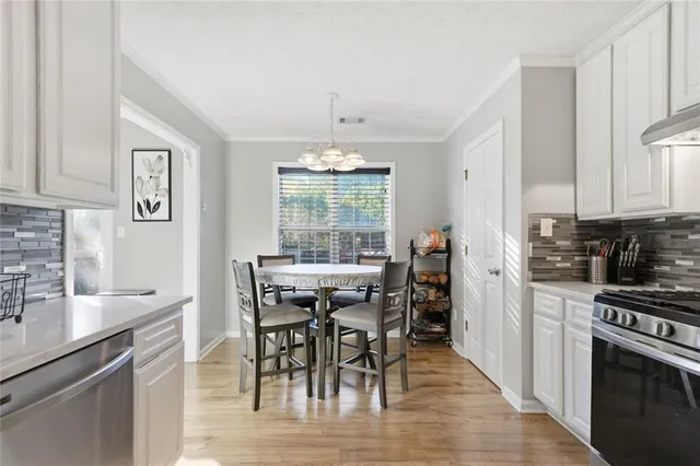 a kitchen with stainless steel appliances granite countertop a stove top oven a sink a dining table and chairs with wooden floor