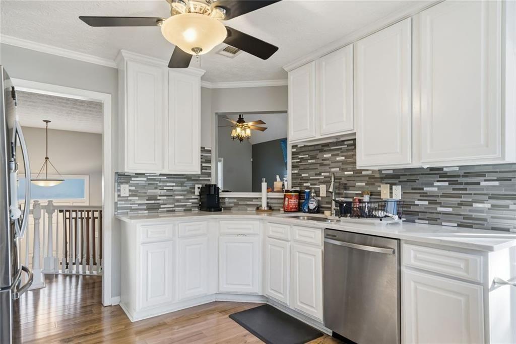 147 Midland Drive Stockbridge, GA 30281 - Photo 9 of 30 a kitchen with a sink dishwasher and white cabinets with wooden floor