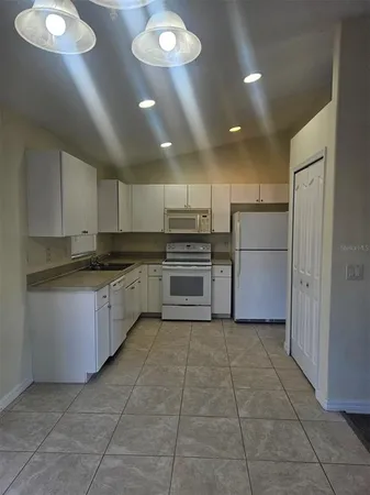 a kitchen with a refrigerator a stove top oven and cabinets