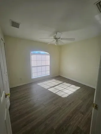 a view of empty room with window and chandelier fan