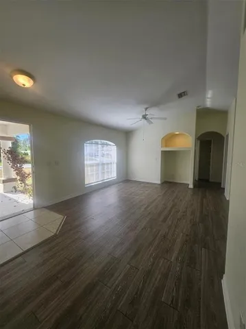 a view of empty room with wooden floor and fan
