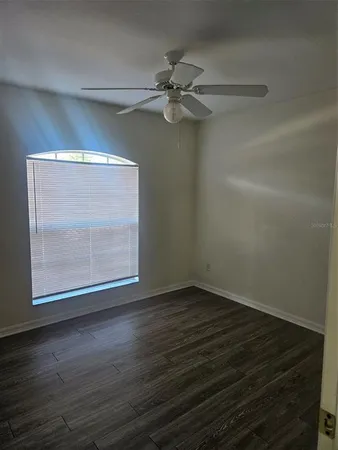a view of an empty room with wooden floor and a window