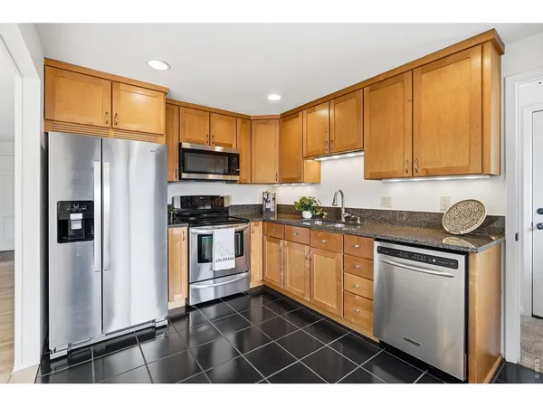 a kitchen with granite countertop a refrigerator stove top oven and sink