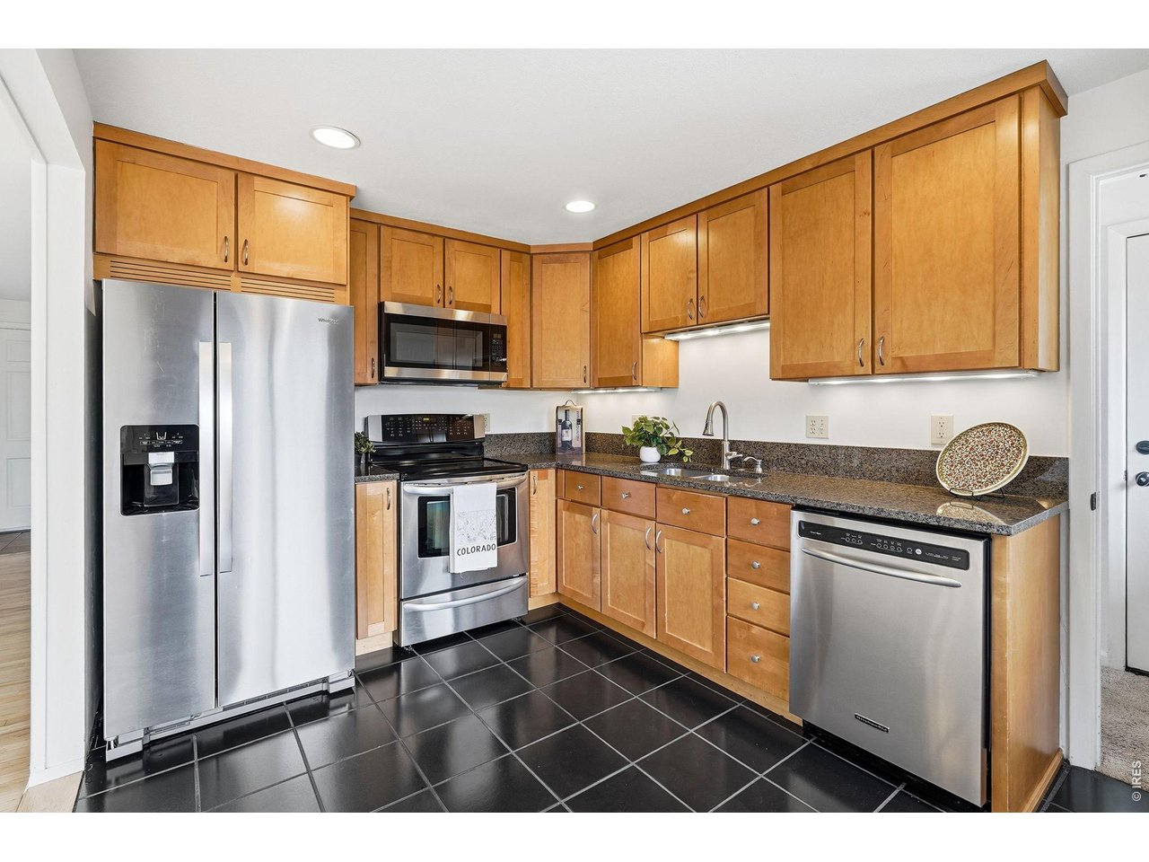 a kitchen with granite countertop a refrigerator stove top oven and sink